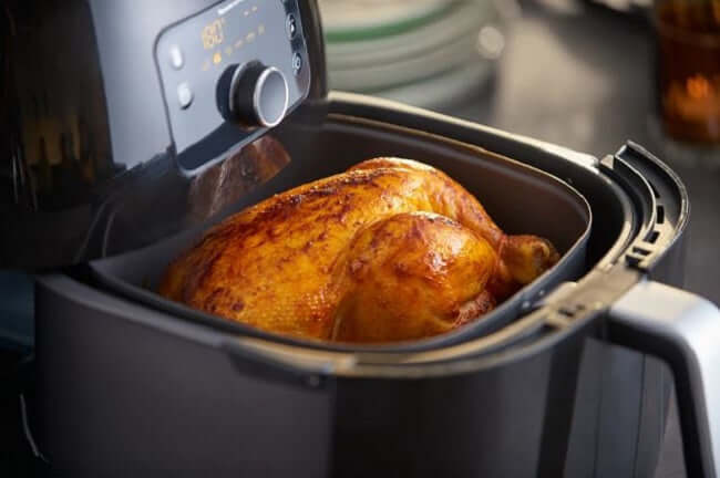 Philips Premium Airfryer XXL HD9651/91 cooking a whole roasted chicken with crispy skin inside the fryer.